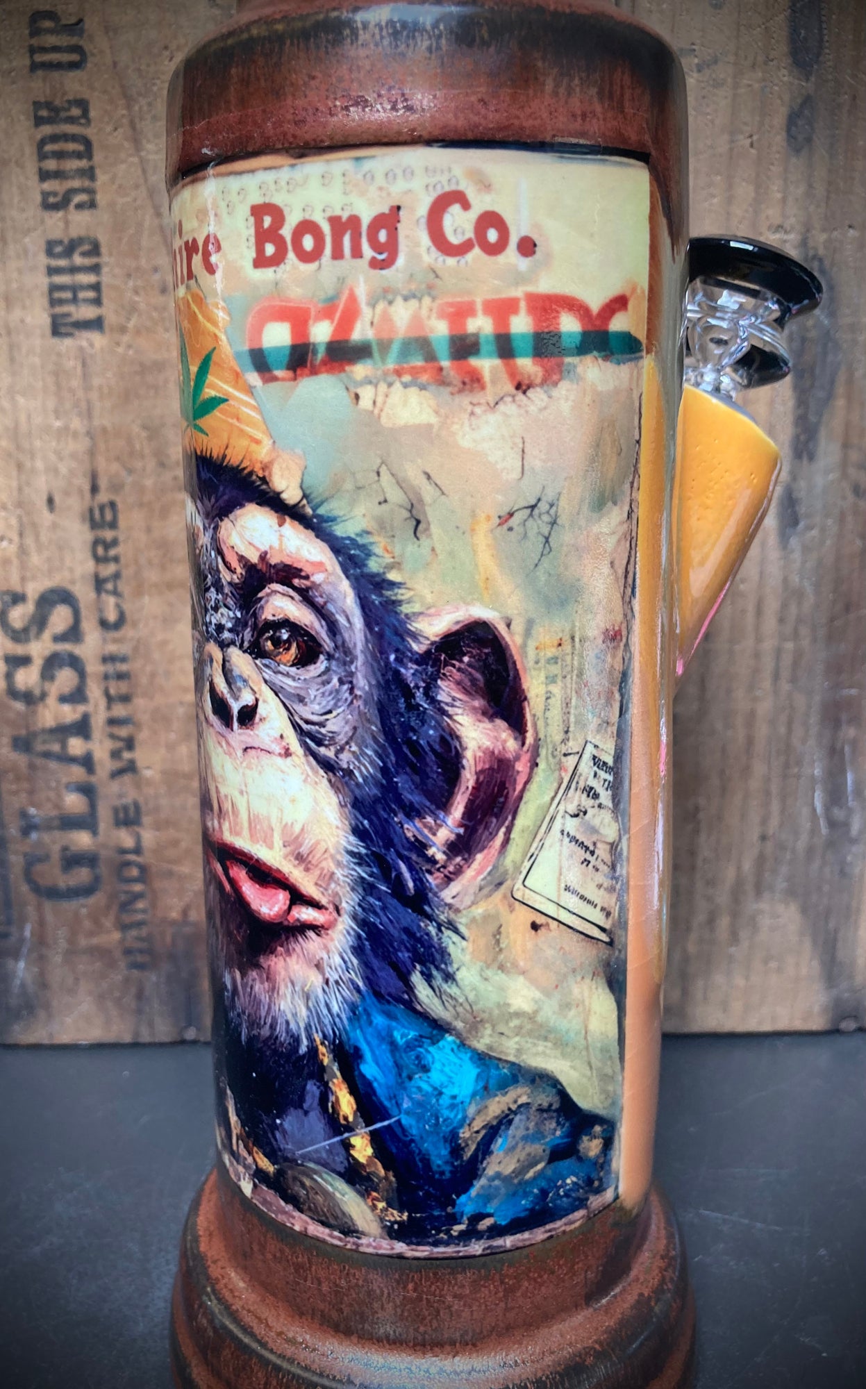 Handmade Ceramic Bong Chimp with Tongue Out Bright Orange Antiqued Copper Glaze. Ceramic bong with glass bowl and wooden base.