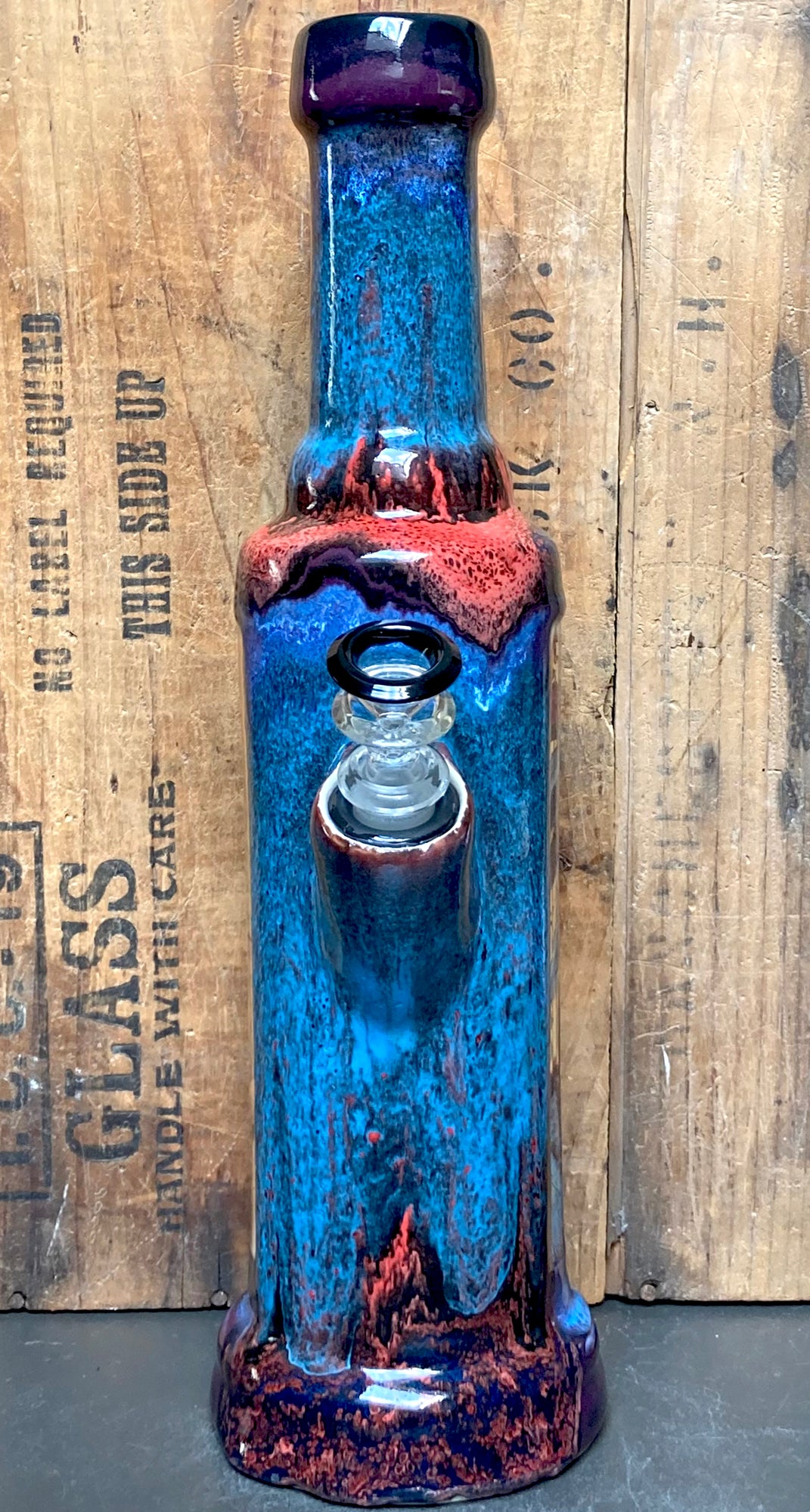 Closeup of the electric blue and crimson glaze dripping down the neck of the bong.