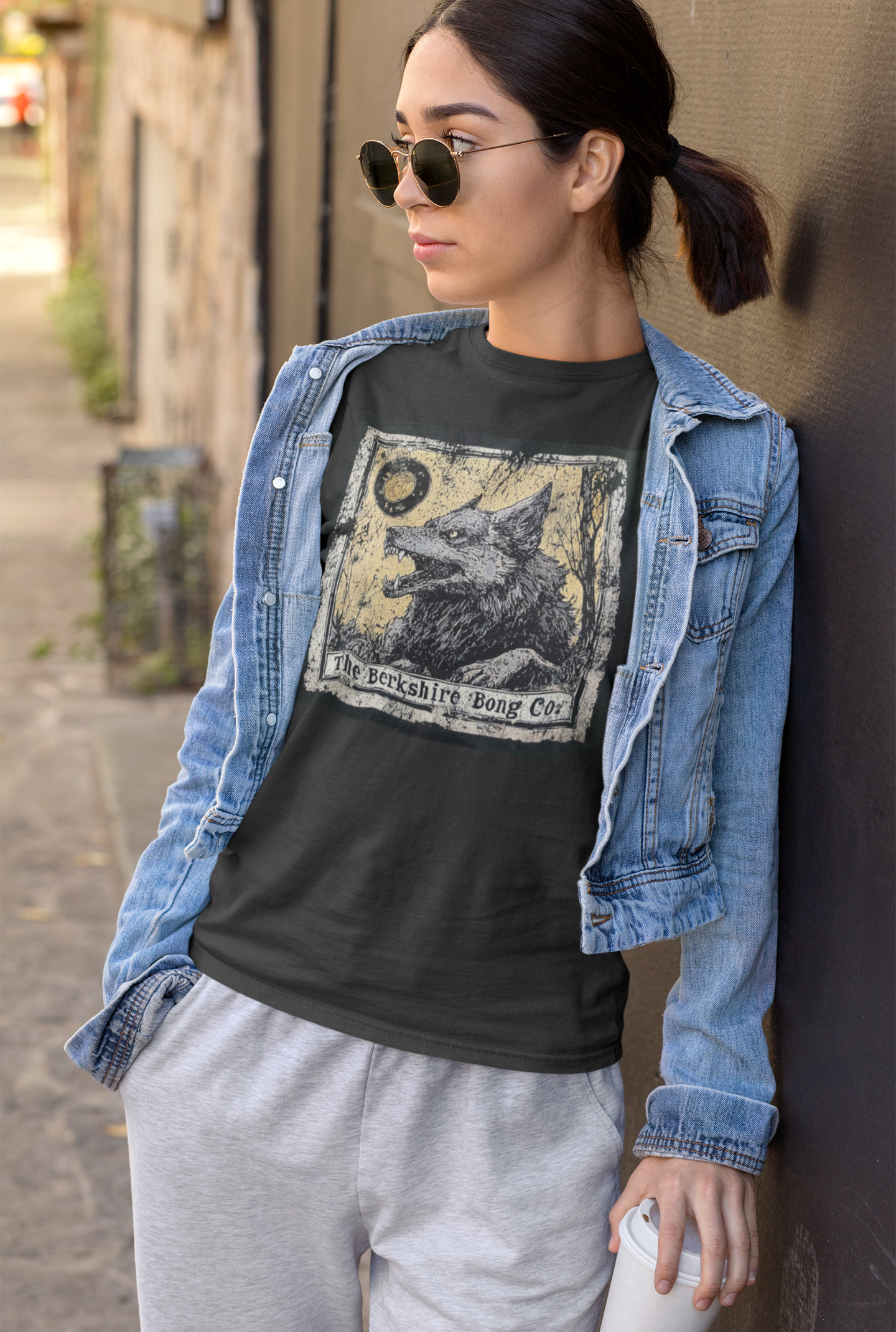 Woman wearing Berkshire Bong Company Big Bad Wolf Graphic Tee with a denim jacket and sunglasses outdoors