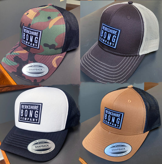 Four Berkshire Bong Company Trucker Hats in various colors and designs with snapback closures