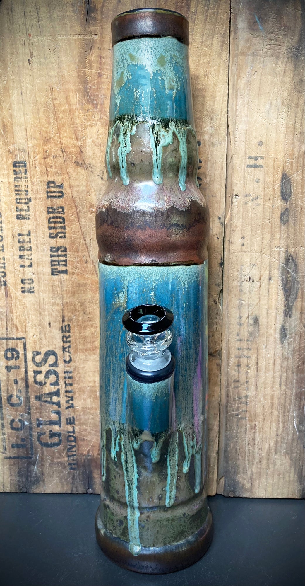 Full view of ceramic bong with layered teal, brown and copper glaze finish and clear glass downstem