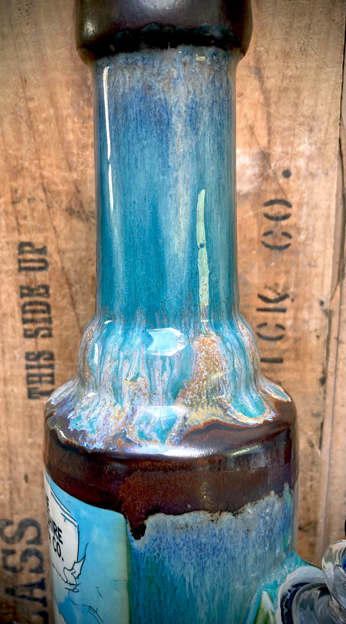 Ceramic bong base showing rich glaze pooling in copper and blue tones.
