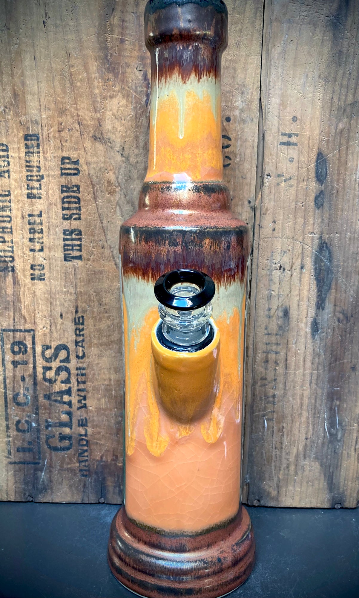 Handmade ceramic bong with glossy orange glaze and antique copper accents.