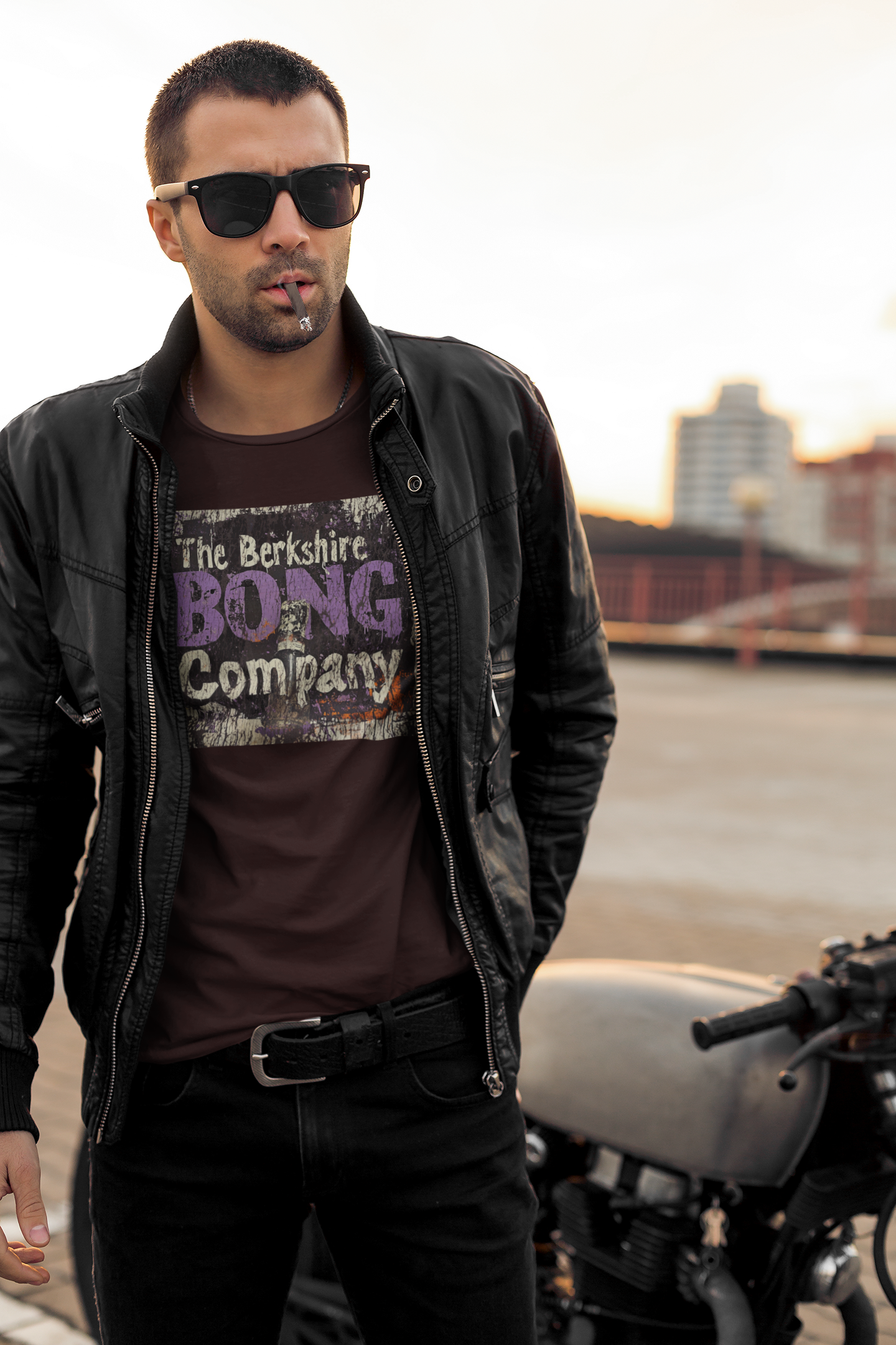Man wearing Distressed Graffiti Logo T-Shirt Vintage Street Art Style Tee in Dark Brown on rooftop with motorcycle