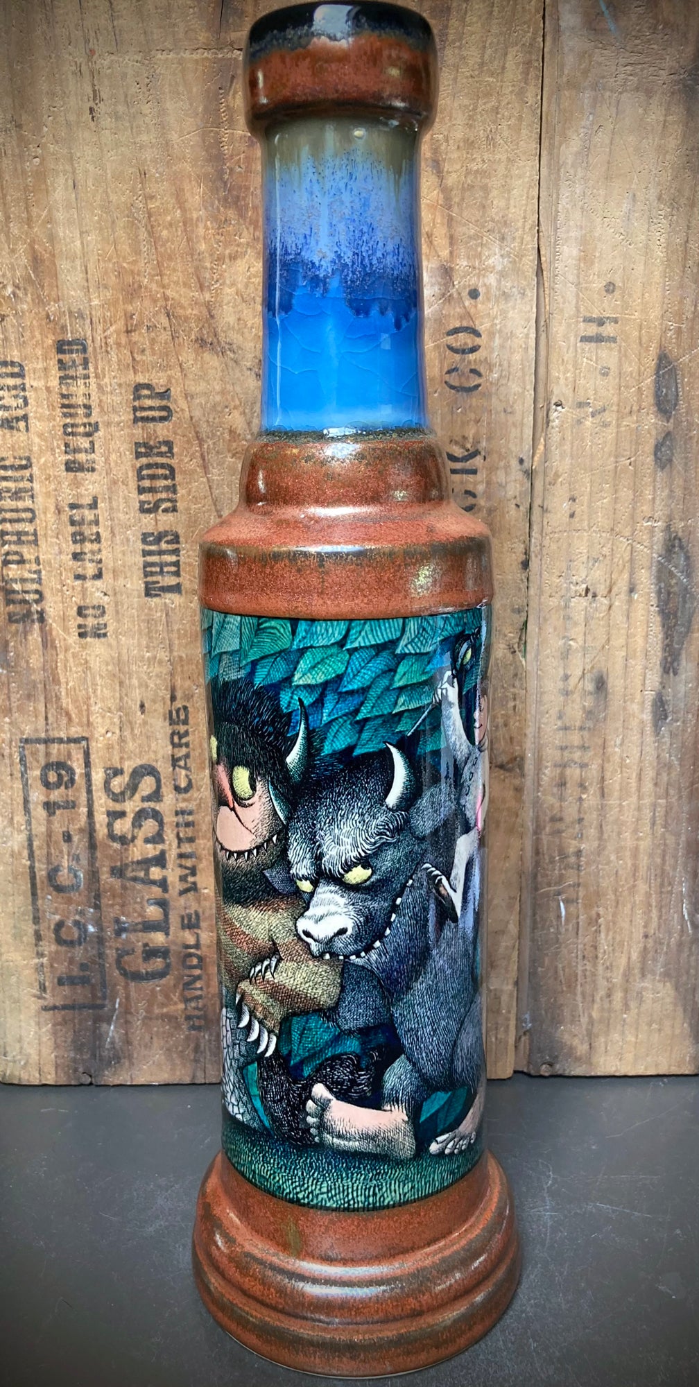 Artistic water pipe glazed in stormy blue and rust, featuring playful monster art