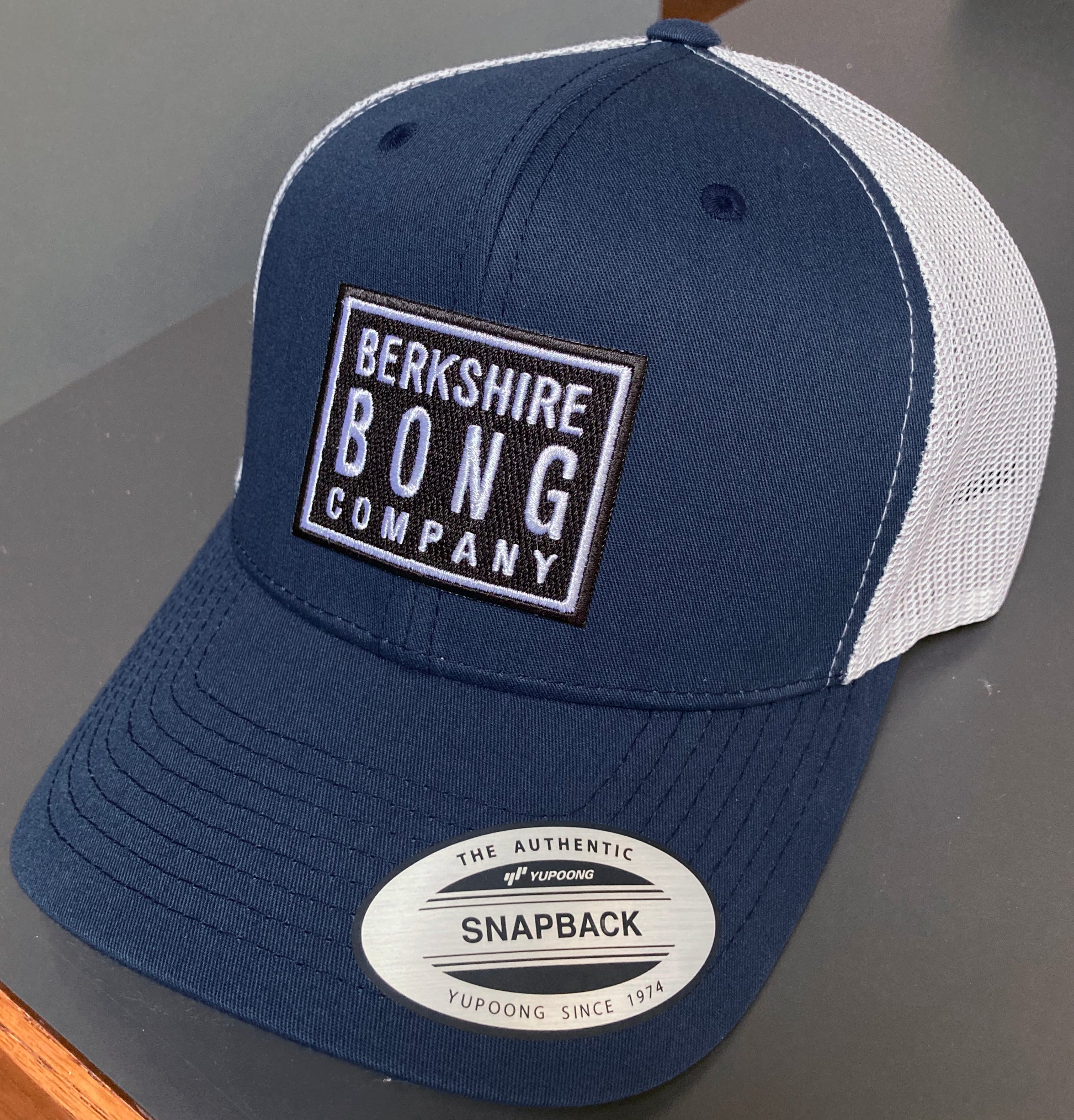 Berkshire Bong Company Trucker Hat in navy blue with a mesh back and embroidered logo