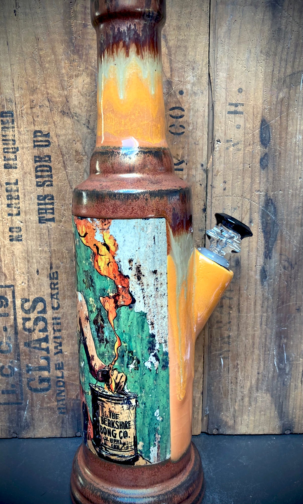 Glossy orange and crackled cream glazes with copper details on ceramic bong.