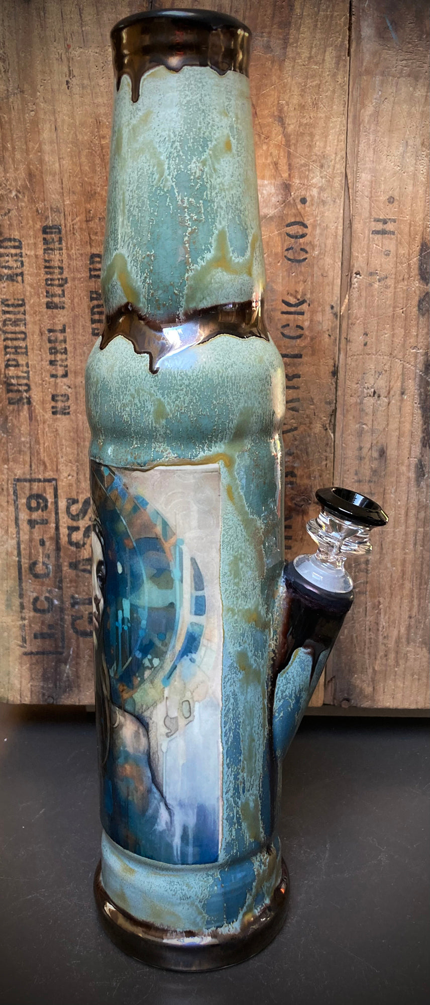 Beautiful water goddess design on ceramic bong with flowing gold and green tones.