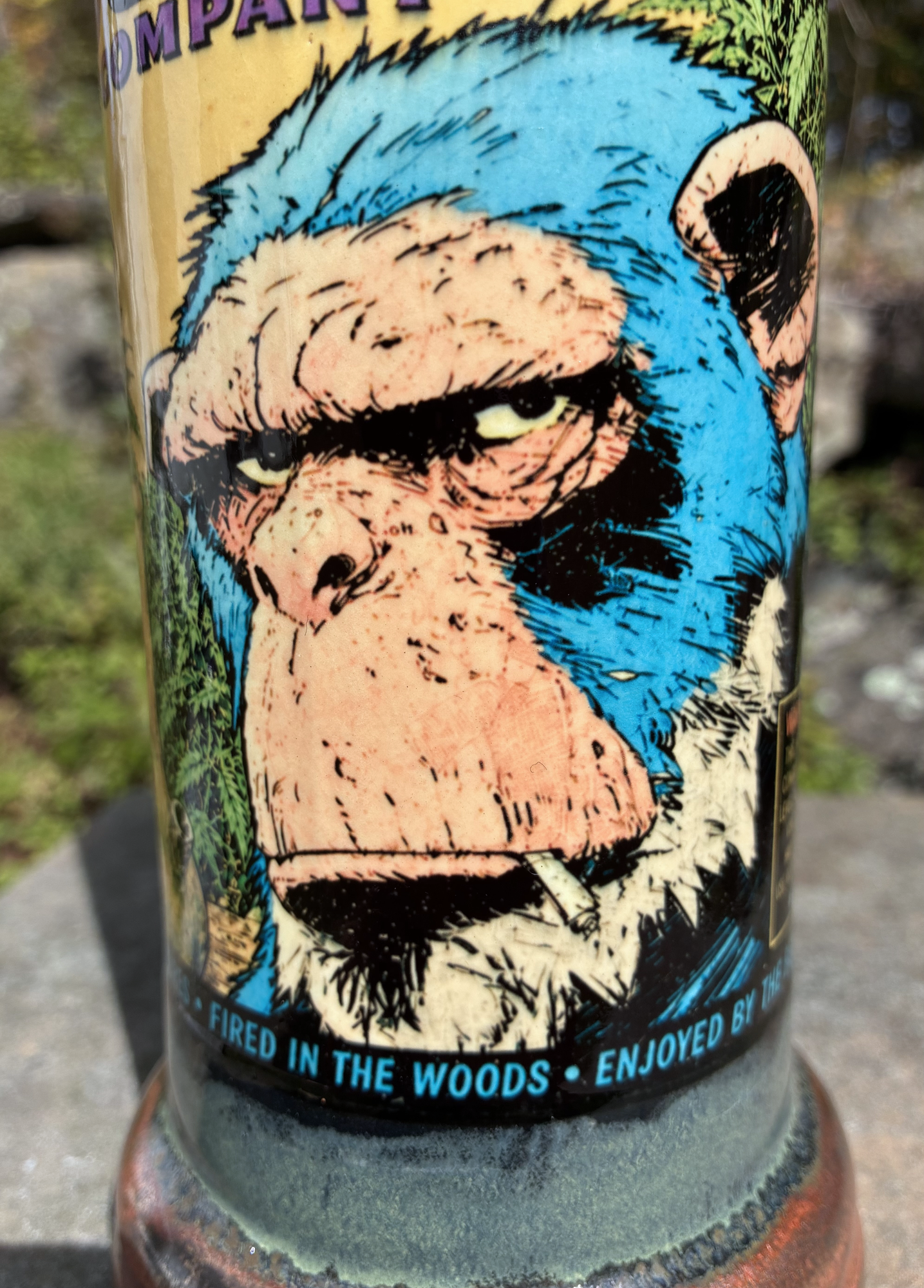Stoned Strong handmade ceramic bong featuring blue chimp comic artwork, mossy green glaze, antique copper accents and a neon yellow-green crackle stripe.